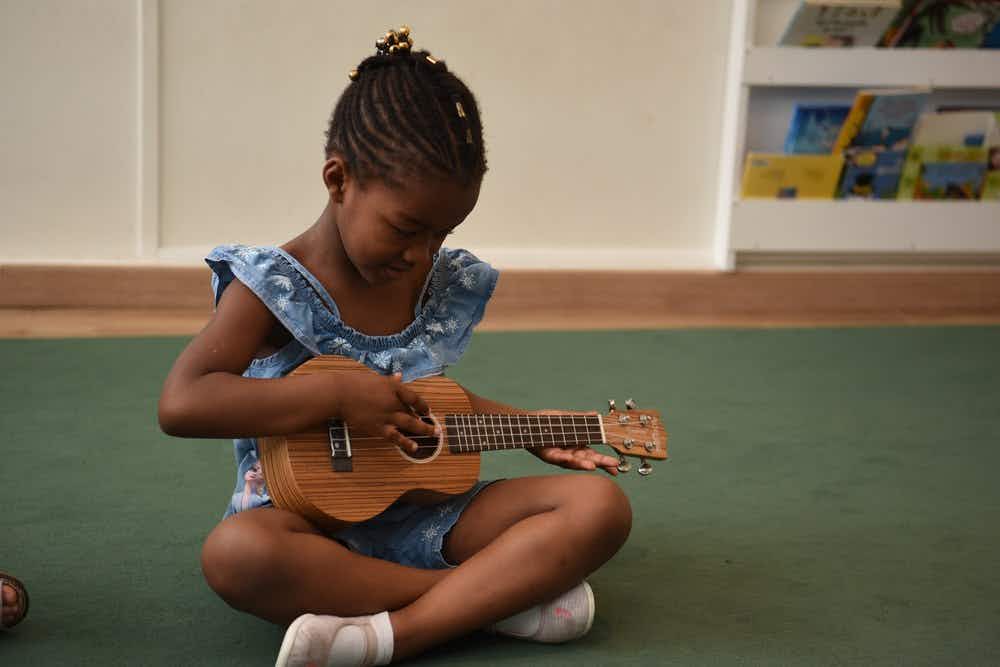 A young girl learns to play guitar in a music school