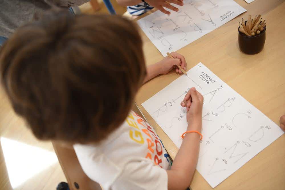 A preschool student learn how to write in English at school