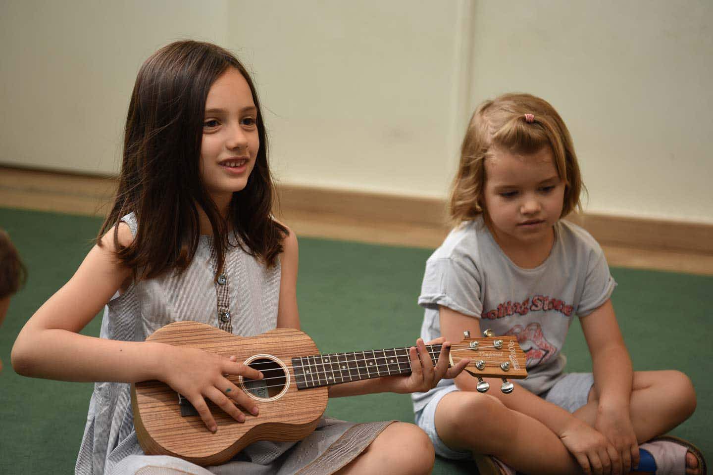 A 5-years-old girl play guitar in a music school classroom