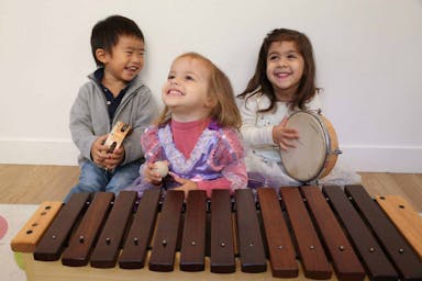Trois enfants développent leur sens du rythme dans un atelier d'éveil musical