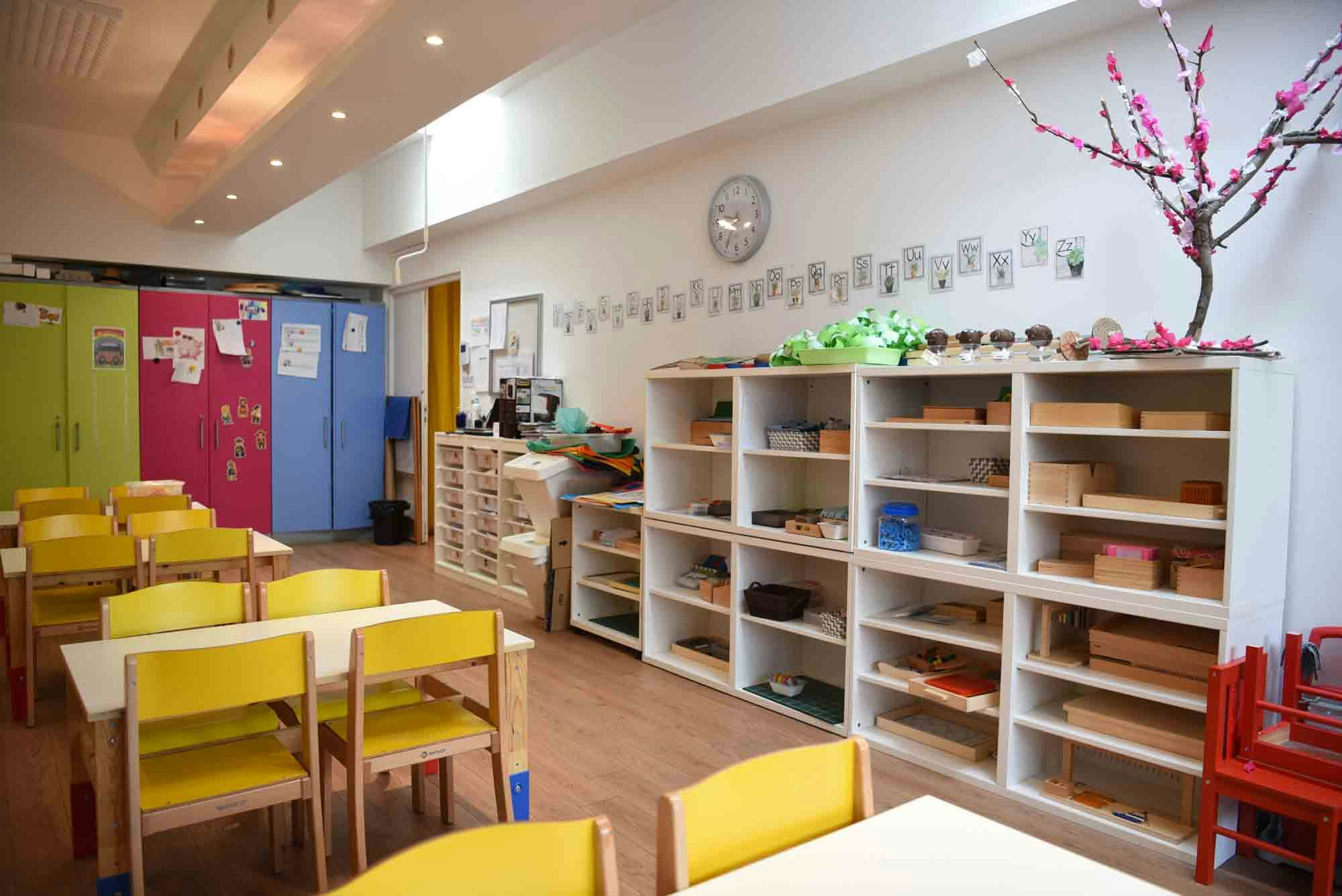 Salle de cours d'école maternelle avec des étagères et un cerisier fait en papier