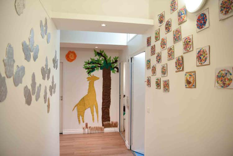 Un couloir d'école maternelle avec une girafe jaune dessinée sur le mur