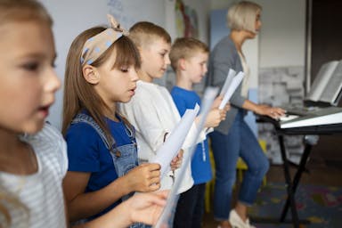 Children sing in a choir while reading their score